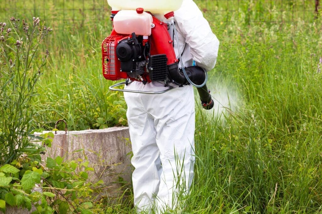 Professional pest control technician spraying for mosquito and tick control in Southern Maine backyard
